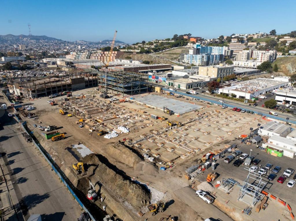Aerial view of campus shows steel structure for parking garage and admin building, as well as forms on the ground where concrete will be poured for the machine shop