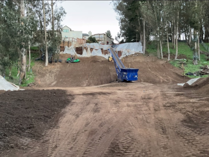 view from base of slope showing machinery adding new material