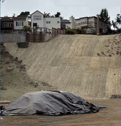 photo of slope shows a smooth surface, covered with mats and topsoil, no vegetation
