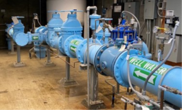 Image of groundwater facility shows a blue pipe with valves and the label "well water"