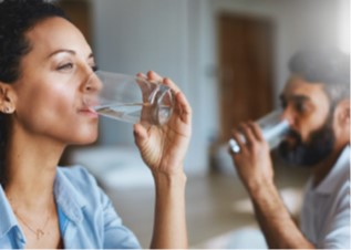 on the left, a woman drinking clear water from a glass and on the right a man drinking water from a clear glass