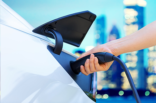 Electric vehicle charging with city in the background