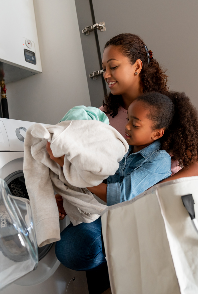 A mother and daughter start a load of laundry