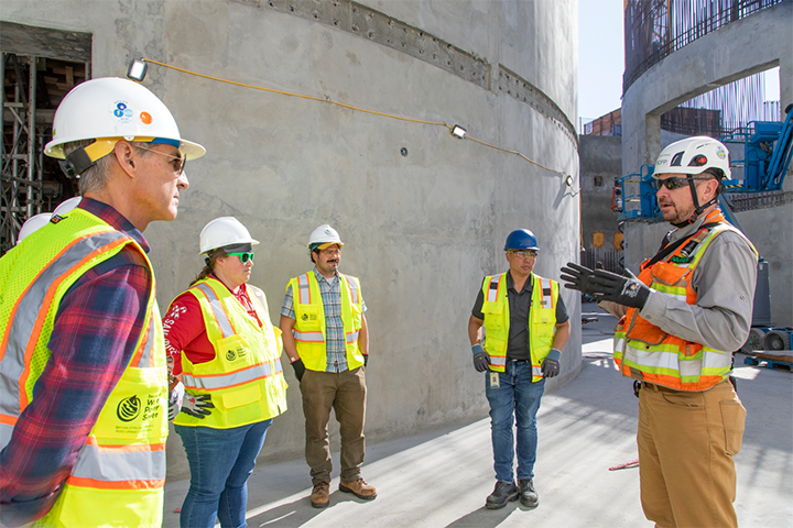 Staff in safety gear standing beside sewer digesters
