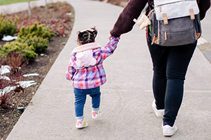 Mother walking her daughter to school and holding hands.