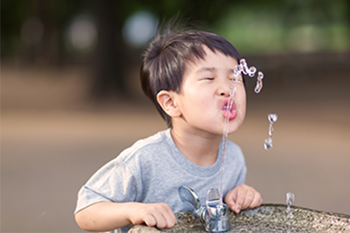 boy drinking from a water fountain
