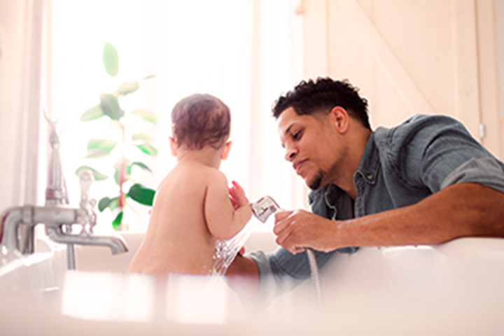 father bathing a baby in a sink basin