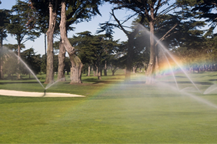 sprinklers watering a golf course fairway
