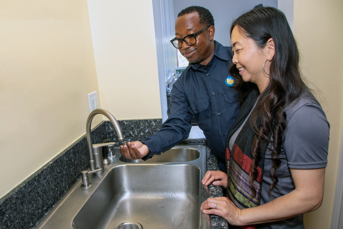 Man showing woman faucet with aerator. 