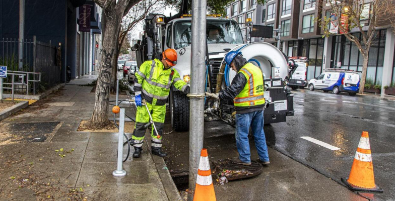 Two men clear a storm drain ahead of rain season.