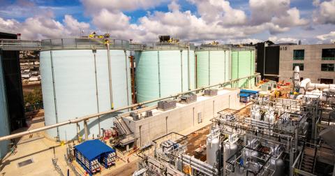 Large industrial storage tanks at a chemical plant under a partly cloudy sky.