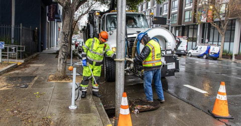 Two men clear a storm drain ahead of rain season.