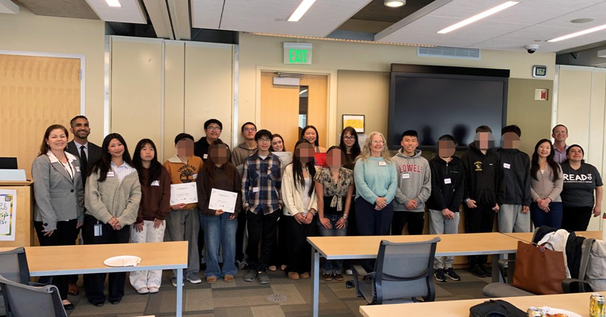 Group of diverse students and SFPUC staff standing in a room, some holding certificates, smiling at the camera.