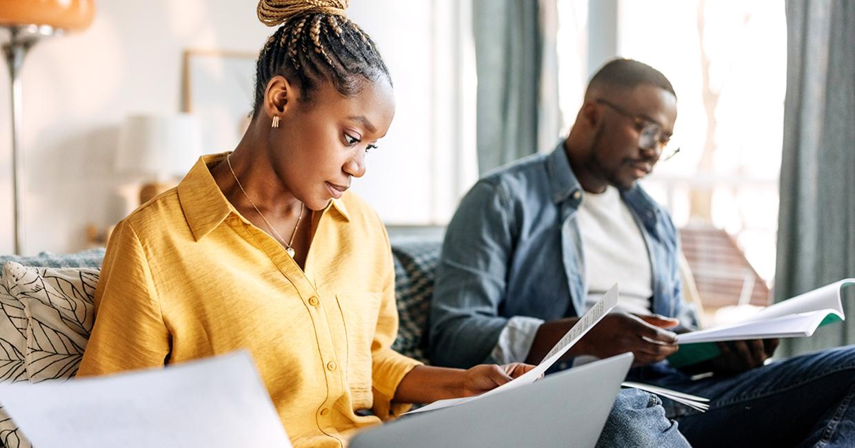 Woman in a yellow short and a man with glasses, both reading.