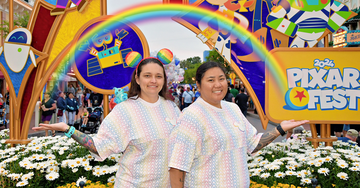 Milyn and her wife, celebrating Pride at Pixar Fest in front of a rainbow