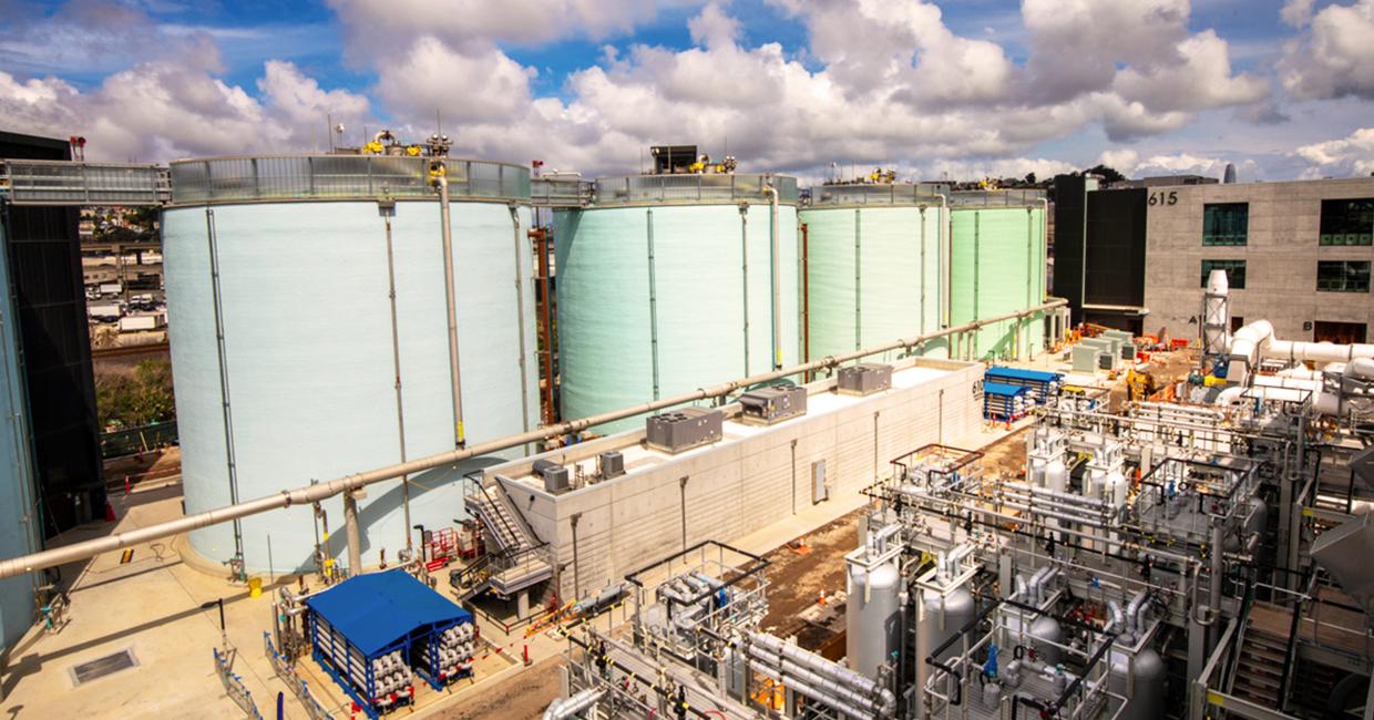 Large industrial storage tanks at a chemical plant under a partly cloudy sky.