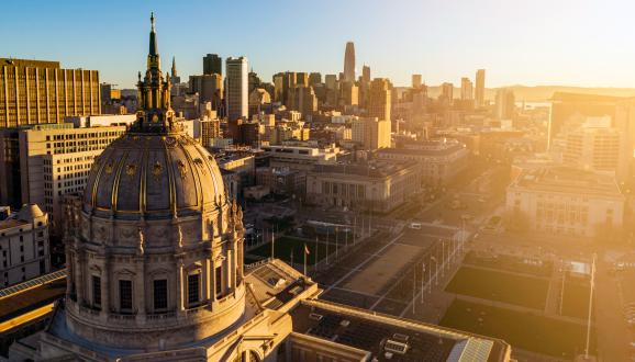 Вид с воздуха на здание мэрии Сан-Франциско с солнечными батареями и городом на заднем плане.