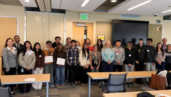Group of diverse students and SFPUC staff standing in a room, some holding certificates, smiling at the camera.