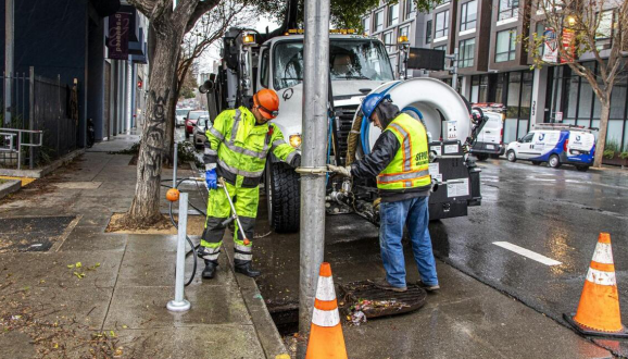 Two men clear a storm drain ahead of rain season.