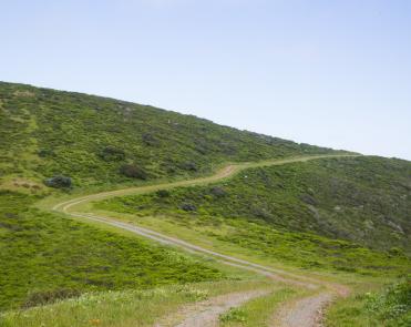 Picture of the Fifield-Cahill Ridge Trail as it cuts through short green grass on the side of a hill